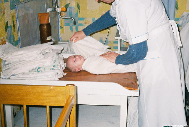 The nurse tightly swaddles the baby before she hands him to Fami.