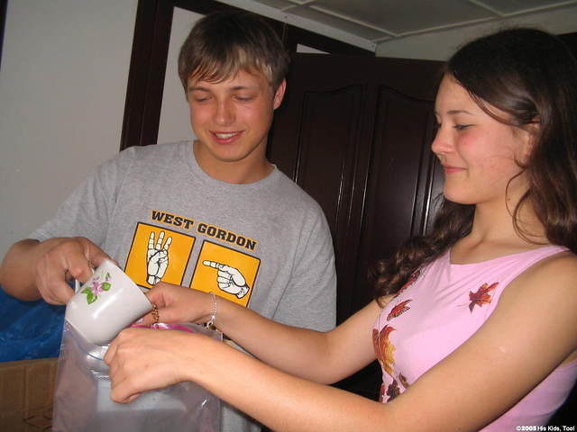Two local teens volunteer to help, by separating rice into bags.