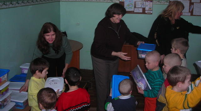 Teresa and Lynn present boxes to the youngest children.
