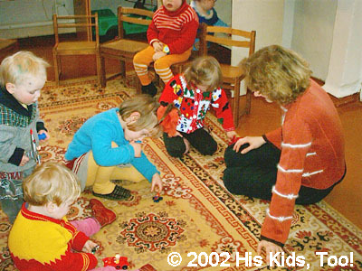 Alla and His Kids, Too! board member, Nikka play with the children on the floor.
