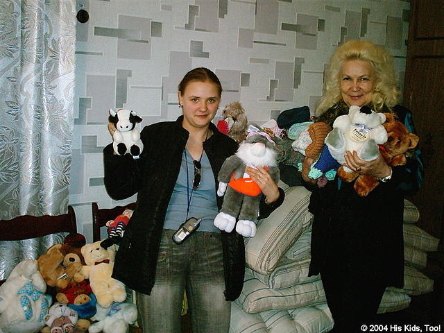 Natasha and the orphanage director stand with the donations of mattresses, sheets, clothing, stuffed animals, toys, and 2 food g