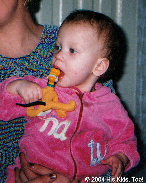 This little girl enjoys her new Pluto dog, even if she is chewing on it!