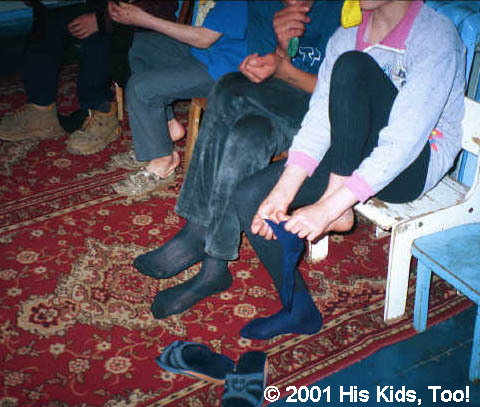 Children put on their new socks on their once bare feet.