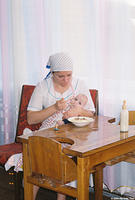 This caregiver is feeding this baby potatoes and a bottle of milk.