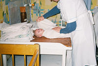 The nurse tightly swaddles the baby before she hands him to Fami.