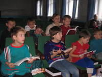 Children follow along in their song books.