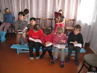 Children at the Shelter sing along.