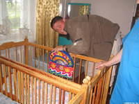 Volunteer Danny W. attaches a 'busy box' to the crib.