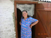 This woman stands in the door way of her very tiny home.