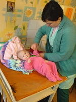 One of the nurses is dressing the child in new clothes, thanks, Anne H., Neve and friends!