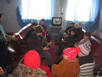 Children patiently await their turn to receive their gifts.  Thie photo is taken indoors, 'look' at how the children are dressed