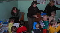 Teresa and Lynn present boxes to the youngest children.