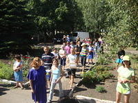 Team members carry aid into the facility surrounded by kids.