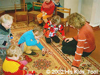 Alla and His Kids, Too! board member, Nikka play with the children on the floor.