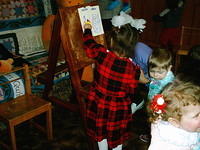 Children here are using new art supplies to draw pictures on the easel.