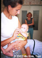 His Kids, Too! Volunteer, enjoys holding this cute baby, wearing new clothes thanks to supporters.