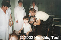 His Kids, Too! Board member, Faye W. makes adjustments to the wheelchair donated by Whitmyer Biomechanix, Inc. while hospital st