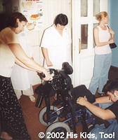 His Kids, Too! board member Faye W. and hospital director look on as Dallas Fillmon makes adjustments to the wheelchairs donated