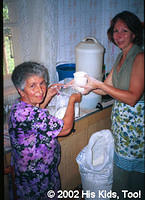 His Kids, Too! Board member, Faye W. and local church member Leza help bag food for widow food bags.